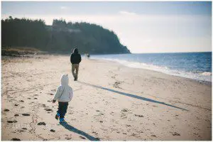 little boy runs after father on beach - family documentary photography