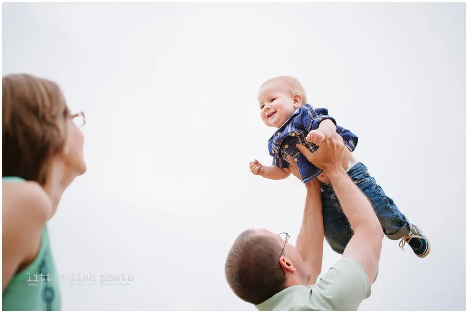 father tosses boy in air while mother looks on