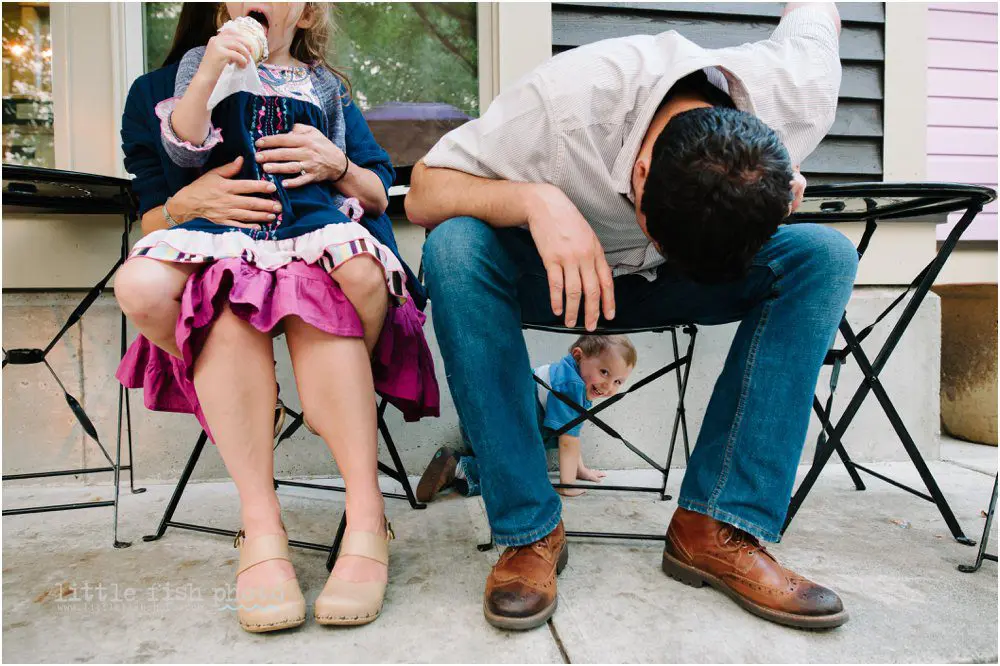 little boy crawls behind chair as father looks under chair