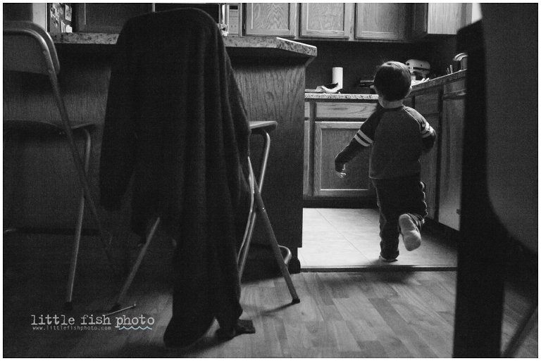 little boy runs through kitchen in black and white - kitsap lifestyle photographer