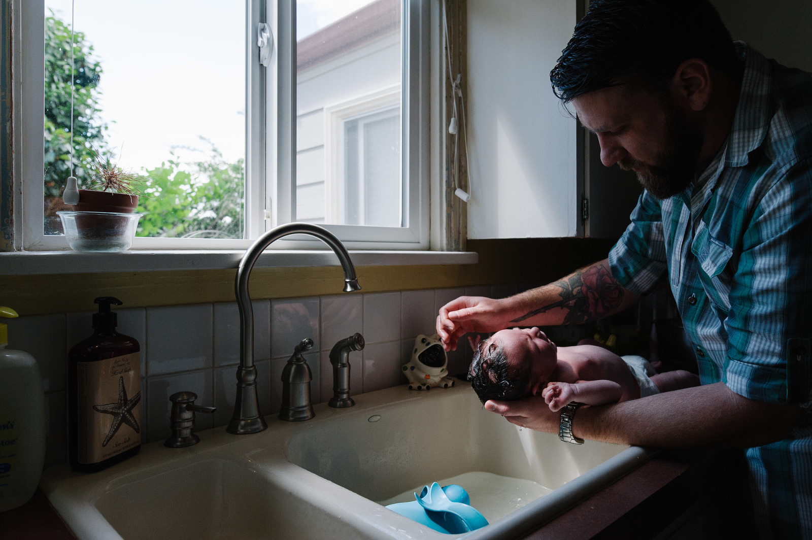 father gives baby sink bath