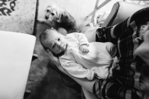 mom holding baby with dog watching on