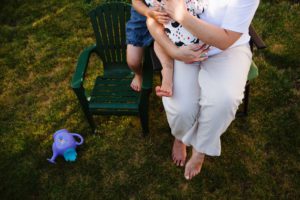 mom cuddles with baby and daughter in lawn chairs