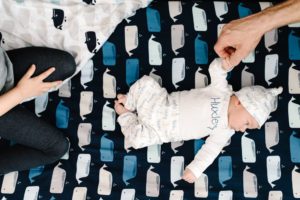 dad holds new baby's hand in crib while sister sits nearby
