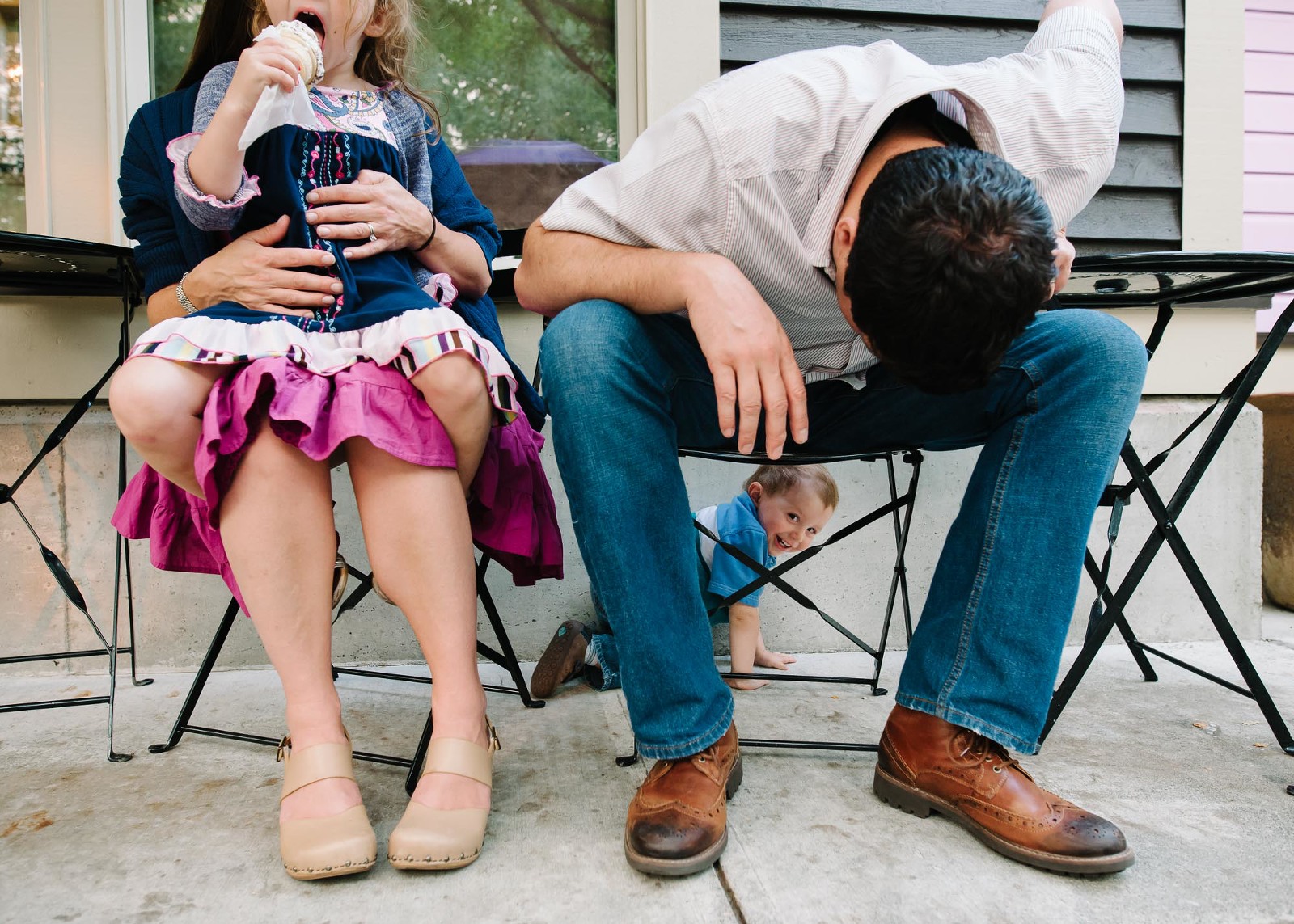 boy climbs under chair outside ice cream parlor