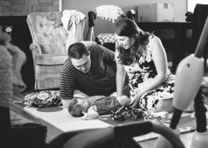 mother and father make faces to baby on floor