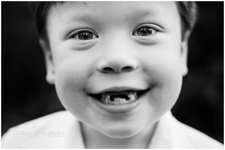 black and white headshot of little boy smiling and missing teeth
