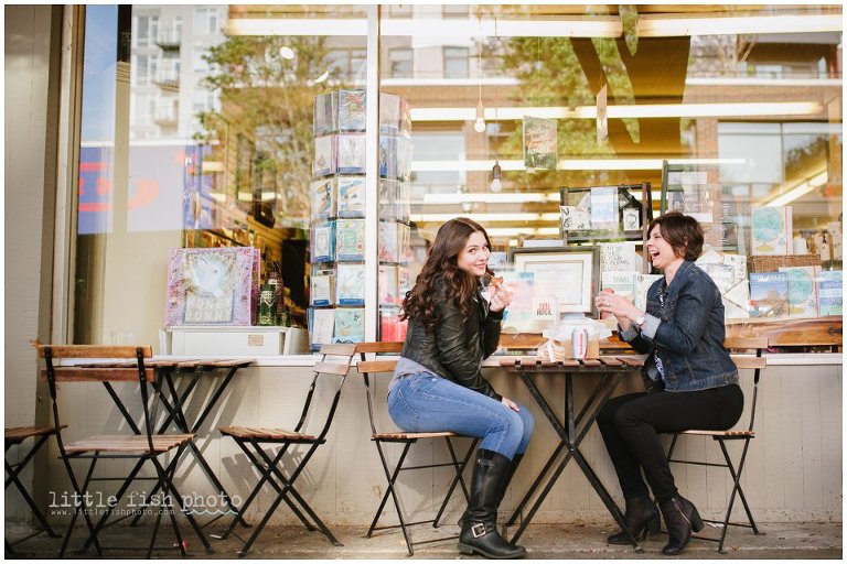 Mom and daughter laugh and have cookies at outdoor cafe table in West Seattle