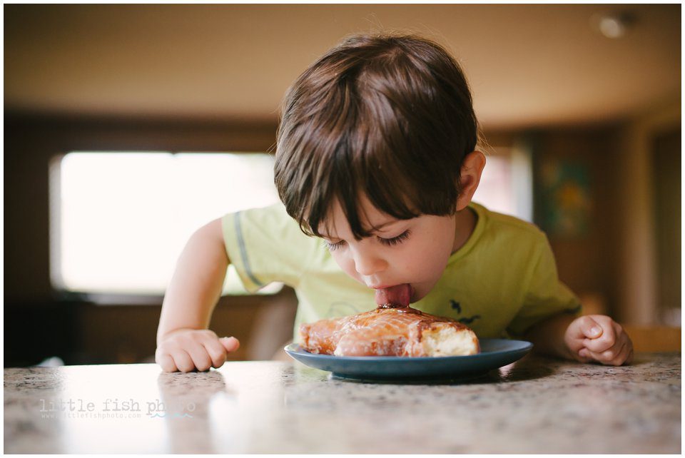 boy licks frosting off doughnut