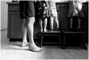 dad and kids stand next to counter while cooking
