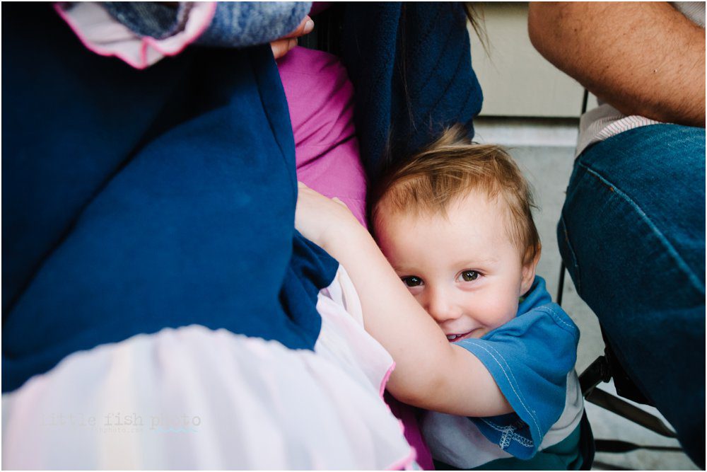 boy smiling and hiding in mom's skirt