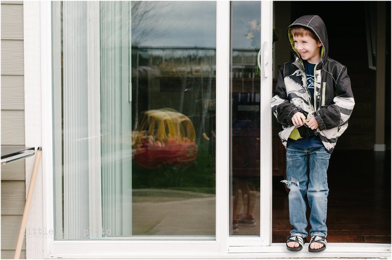 boy stands in backyard doorway