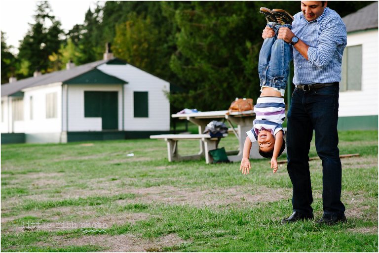 father holds happy son by ankles