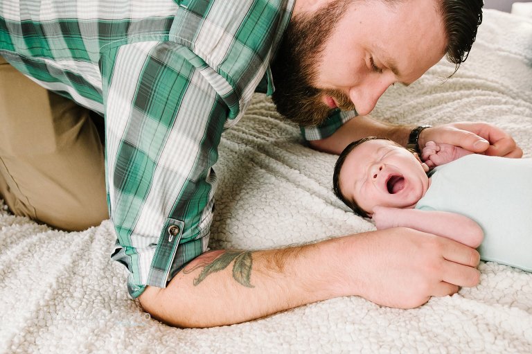baby yawns as father looks on - Bremerton Lifestyle Newborn Photographer