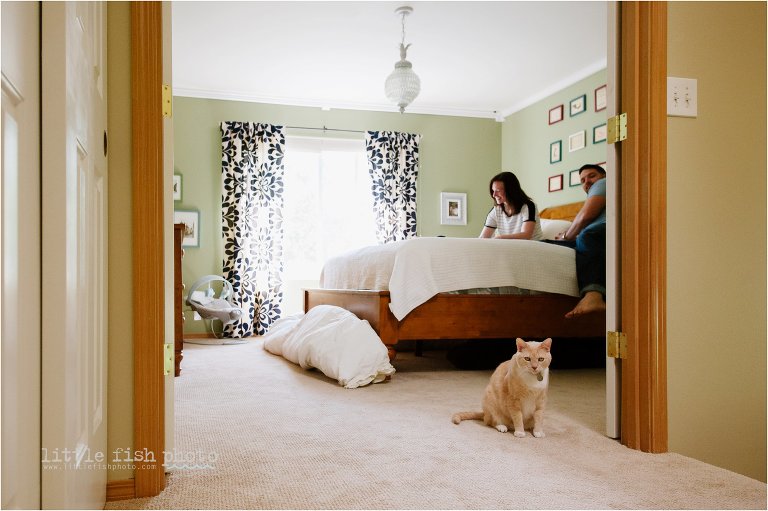 family in bedroom as cat watches from doorway