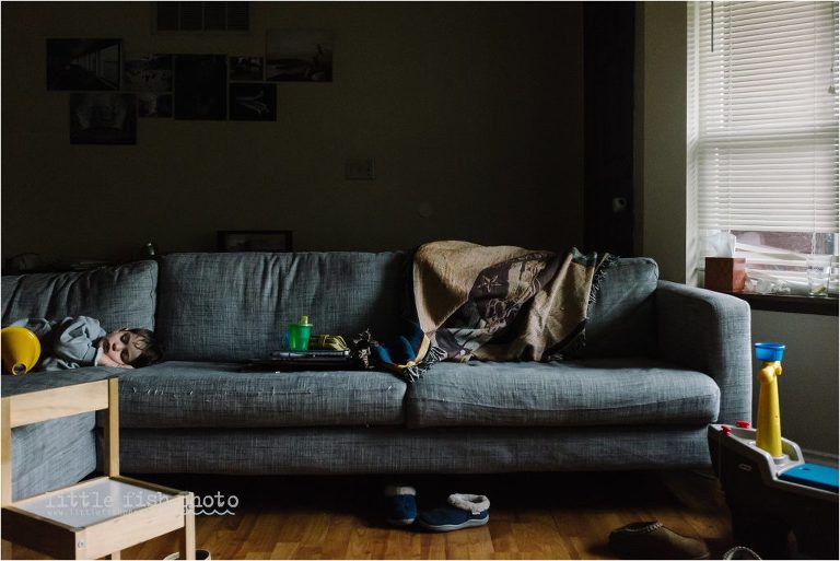 boy asleep on cluttered couch - documentary family photography