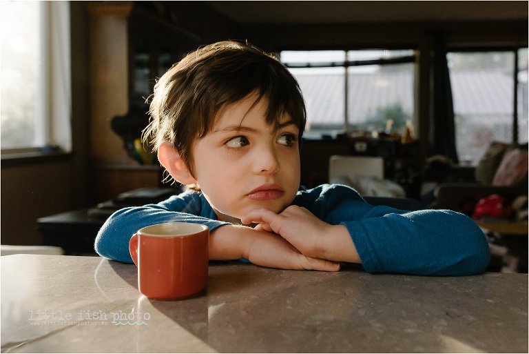 boy makes side eye with little cup of warm beverage