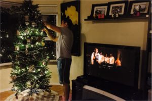man decorates christmas tree