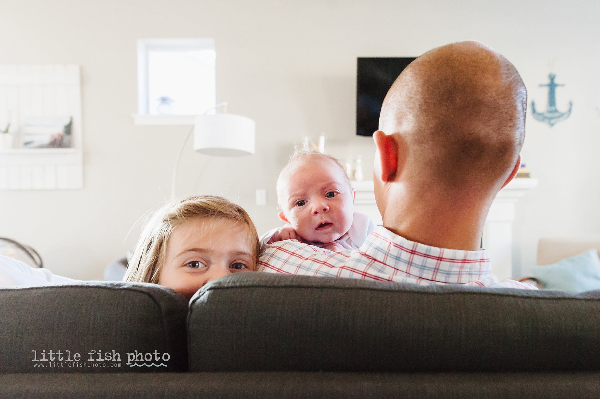 baby and girl peer over couch - Kitsap Lifestyle Newborn Photographer