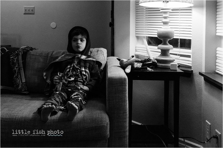 kid watching tv on couch in hooded sweatshirt