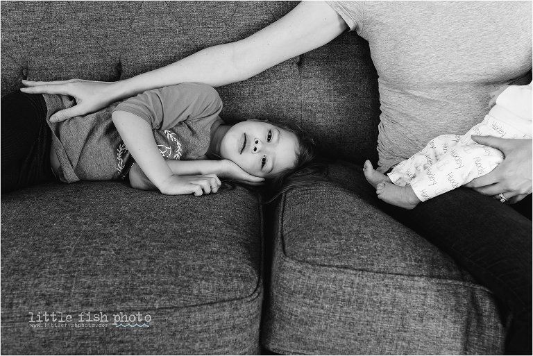 mom holds baby and reaches to rest a hand on girl laying down