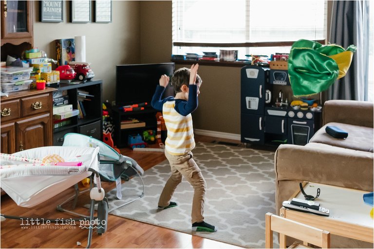 boy throws toy cape on couch - Documentary Family Photography