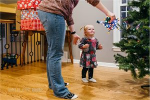 mom helps toddler girl with christmas lights - Kansas City Documentary Family Photographer