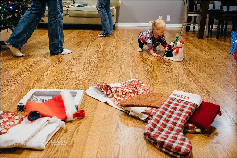 toddler plays with decorations while parents work behind her - Kansas City Documentary Family Photographer