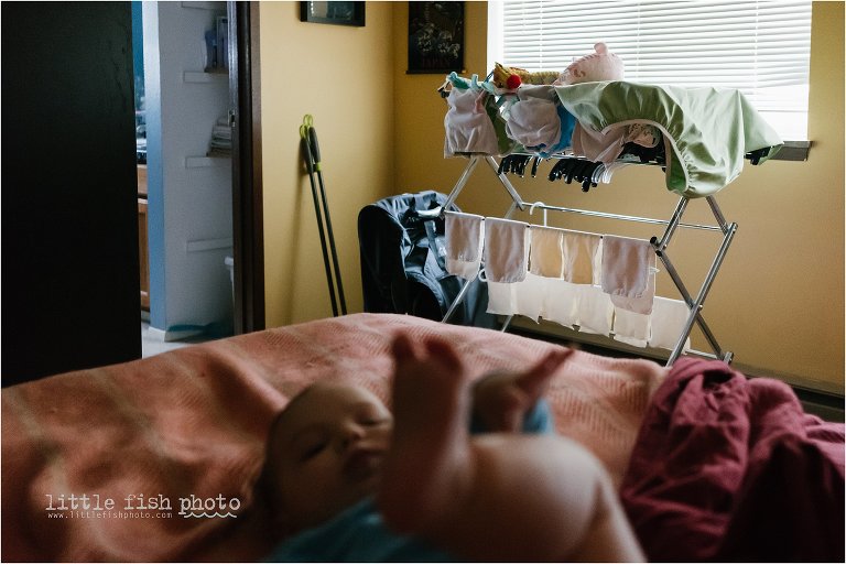 Baby on bed with cloth diapers drying