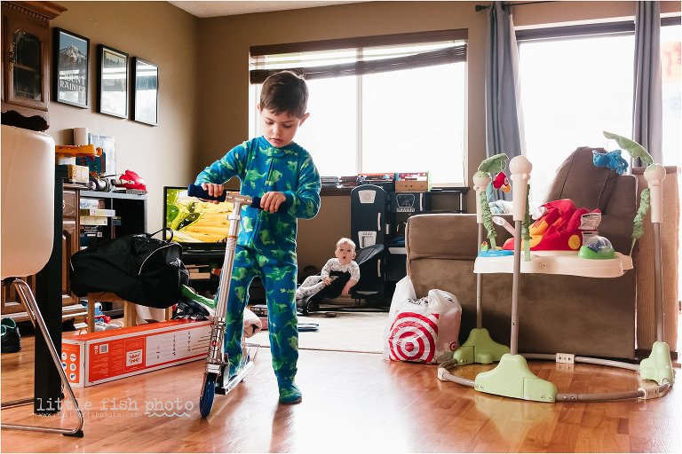 boy rides scooter while baby looks impressed