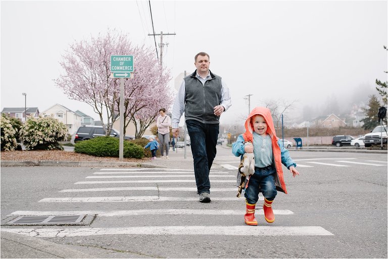 father crosses street while son leads the way