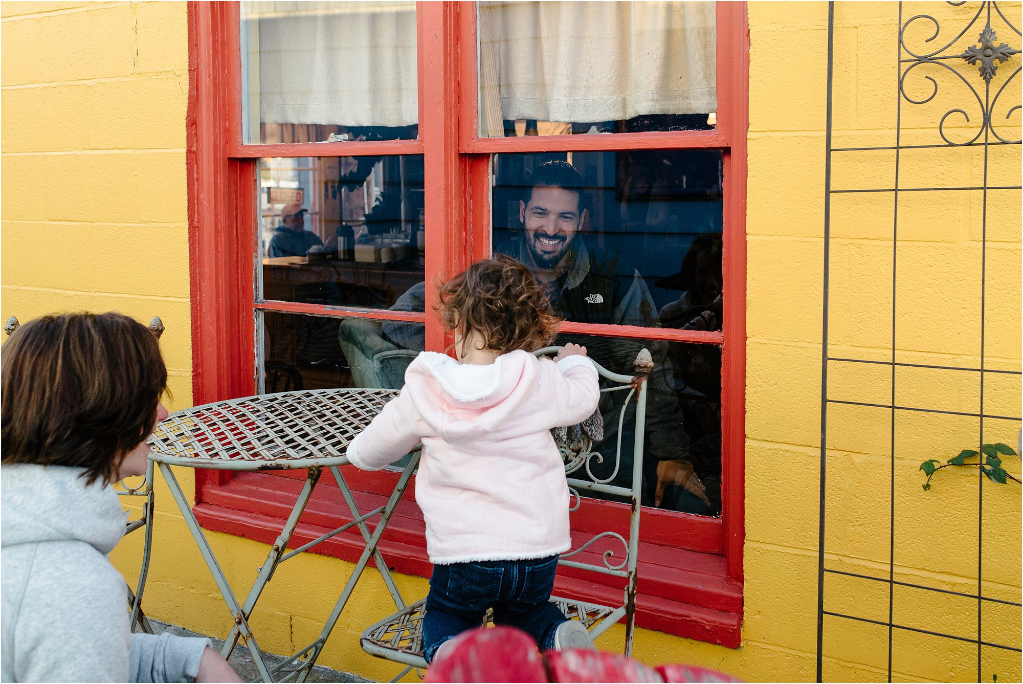 father peers through window at daughter - Kitsap Family Photographer