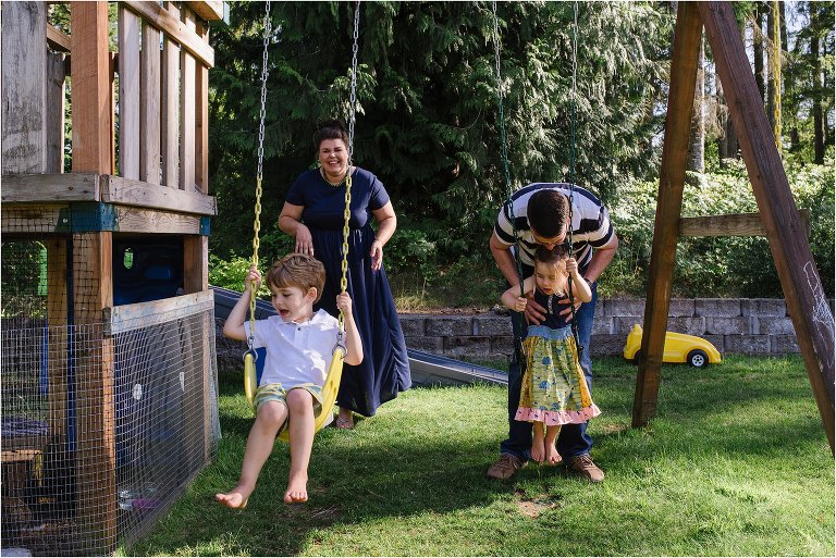 mother and father push kids on swings