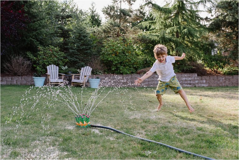 boy plays in sprinkler