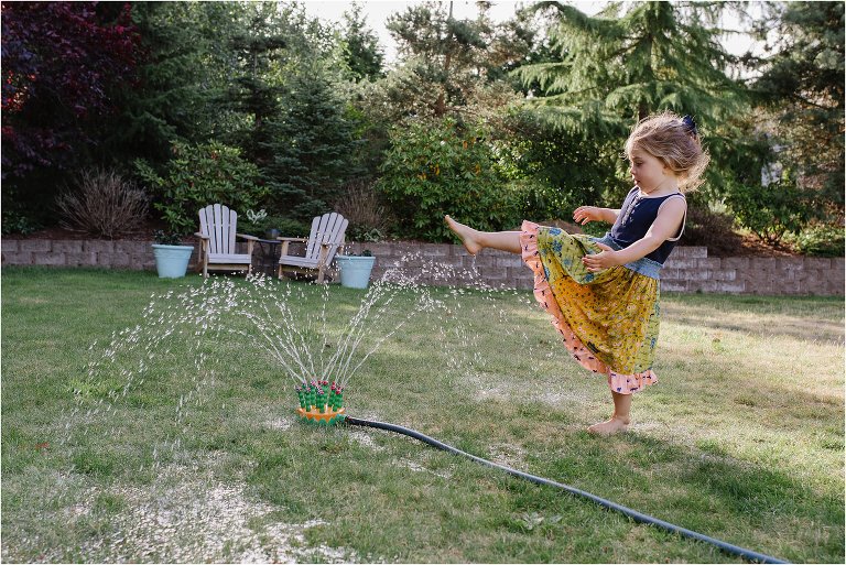 girl plays in sprinkler