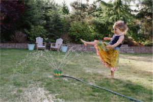 girl plays in sprinkler