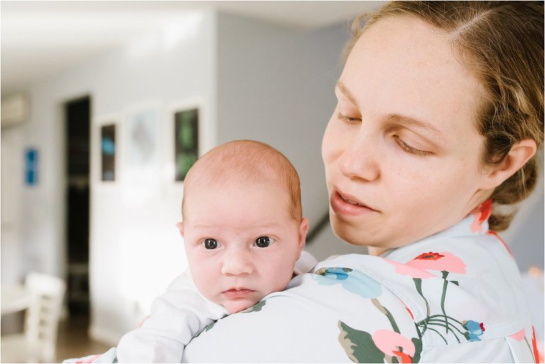baby peers over mom's shoulder - Poulsbo Lifestyle Newborn Photographer