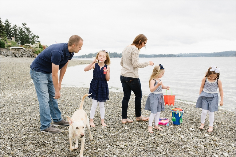 Documentary photography of family playing on beach in Bremerton Washington. Family has buckets and is blowing bubbles.