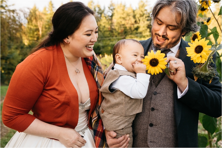 mom and dad tickle baby's face with sunflower
